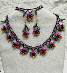 a necklace and earring set made out of multicolored bead flowers on a white mannequin