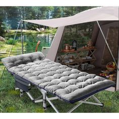 an outdoor bed with a canopy over it in the grass next to a body of water