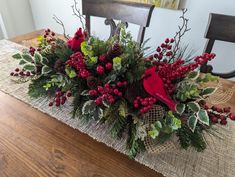 a christmas centerpiece on a table with red berries and greenery in the center