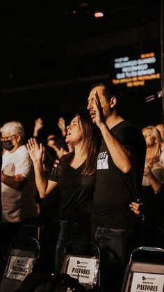 two people standing next to each other with their hands up in the air and clapping