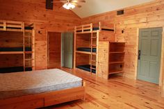 a bedroom with wooden walls and flooring has bunk beds on each side of the room