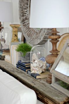 a table with some books and vases on top of it next to a mirror