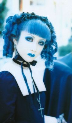 a woman with blue hair wearing a black and white outfit