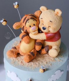 a winnie the pooh and tigger figurine on top of a cake