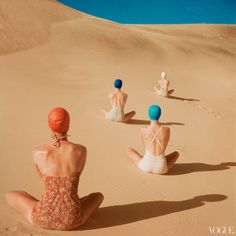 three women sitting in the sand with their backs to each other and one is wearing a bathing suit