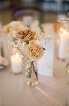 the centerpieces on this table are filled with flowers, candles and napkins