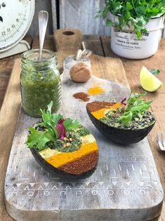 three bowls filled with different types of food on top of a wooden table next to a clock