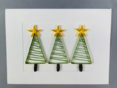 three green christmas trees with yellow stars on them are mounted to a white card that says merry