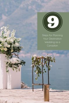 two white vases with flowers and greenery in them on a dock near the water