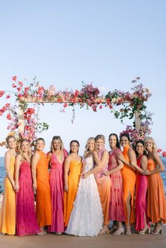 a group of women standing next to each other in front of a flower covered arch