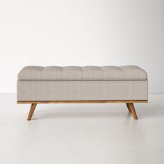 an upholstered bench with wooden legs and a light colored fabric seat cover on it