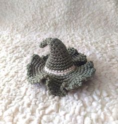 a small crocheted toy sitting on top of a white bed covered in blankets