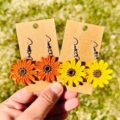 two yellow and orange flowers are being held in front of each other by a person's hand