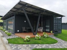 a black container house sitting on top of a lush green field