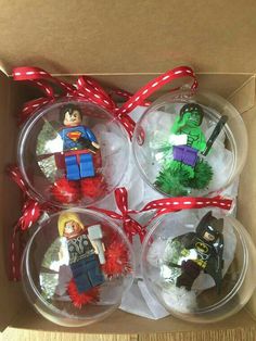 four christmas ornaments in a box with red ribbon and lego characters on them, all wrapped up