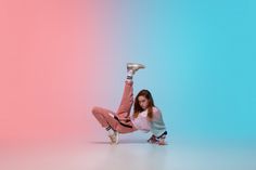 a young woman is doing a handstand on her knees in front of a pink and blue background