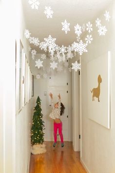 These snowflake decorations are a super fun way to surprise your kids during the winter holidays! Put them up overnight and the kids will wake up to a snow flurry indoors. Check out our simple tutorial and the easy trick to cutting your snowflakes. Love this idea for kid Christmas decorations. Snow Flake Garland Diy, Winter Wonderland Playroom, Children Christmas Decorations, Children’s Christmas Decorations, Snowflake Home Decor, Homade Christmas Decorations Diy, Christmas House Decor Diy, Kids Playroom Christmas Decor, Christmas Banister Decorations Railings