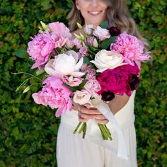 a woman holding a bouquet of pink and white flowers