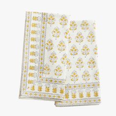 two yellow and white napkins on top of each other, one with an ornate design