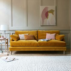 a living room with a yellow couch and two chairs next to a painting on the wall