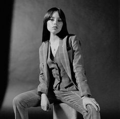 a woman sitting on top of a cement block wearing a suit and tie, posing for a black and white photo