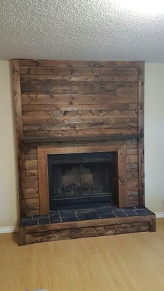 an empty living room with a fireplace and wood paneling