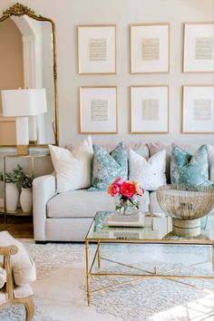 a living room filled with white furniture and lots of pictures on the wall above it