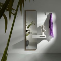 a white shelf with a purple scarf hanging from it's side next to a potted plant