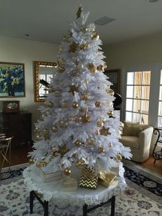 a white christmas tree decorated with gold ornaments