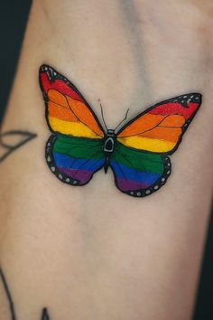 a colorful butterfly tattoo on the side of a woman's leg with black ink