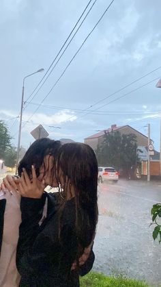 two people standing in the rain with their hands covering their faces