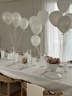 the table is set with white balloons and candles