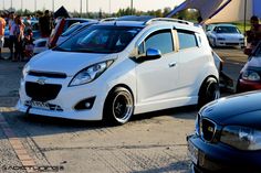 a small white car parked next to other cars