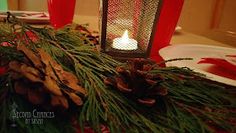 a candle is lit on a table with pine cones