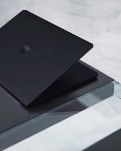 an apple laptop sitting on top of a glass table