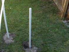 two white poles sticking out of the ground in front of a fence and grass area