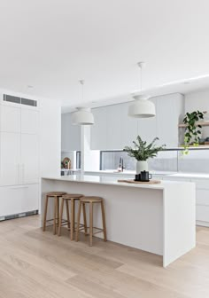 a kitchen with two stools and an island in the middle, surrounded by white cabinets