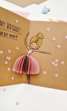 a handmade birthday card with a ballerina dancer on the front and pink folded paper in the back