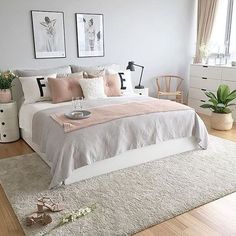 a bedroom with white and pink bedding, pictures on the wall and rugs