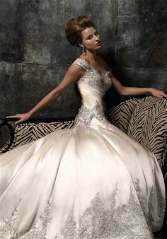 a woman in a wedding dress sitting on a zebra print chair and posing for the camera