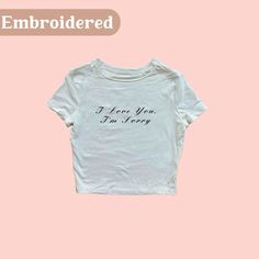 I Love You, I'm Sorry Crop Top/Baby Tee in Black thread Fit & style - Short-sleeve tee - Cropped length - Soft fabric blend with stretch - Crewneck style - Solid hue Trendy Short Sleeve Tops With Letter Embroidery, Fitted Crew Neck Tops With Embroidered Text, Fitted Cotton Tops With Embroidered Graphics, Trendy Fitted Embroidered T-shirt, White Embroidered Basic Top, Cute Crew Neck Top With Embroidered Text, Fitted T-shirt With Embroidered Text And Short Sleeve, Trendy White Tops With Letter Embroidery, Cute Embroidered Short Sleeve Tops