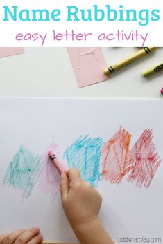 a child's hand writing on a piece of paper with colored crayons