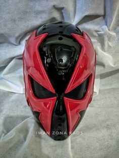 a red motorcycle helmet sitting on top of a white sheet