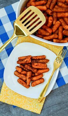 there is a white bowl filled with baby carrots next to a fork and knife