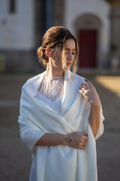 a woman wearing a white shawl is standing outside