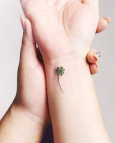 a small four leaf clover tattoo on the left wrist and right hand with a tiny one