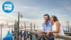 a man and woman standing on a bridge next to water with boats in the background