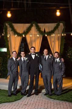 a group of men standing next to each other in front of a gazebo at night