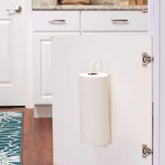 a roll of toilet paper is hanging on the wall in front of an open refrigerator