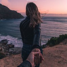 two people holding hands while looking out at the ocean and mountains with text overlay